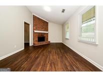 Inviting living room with striking brick fireplace and rich, dark wood-look flooring at 6194 Golden Meadow Court Ct, Riverdale, GA 30296