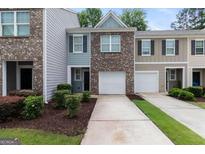 A brick townhouse with attached one car garage and lush landscaping at 3155 Tarian Way, Decatur, GA 30034