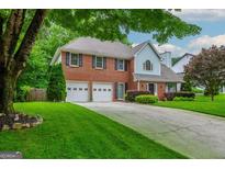 Charming two-story home with a well-manicured lawn, a brick facade, and an attached two-car garage at 10980 Pinehigh Dr, Alpharetta, GA 30022