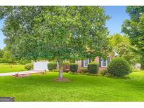 Well-maintained lawn and mature tree enhance the curb appeal of this brick home at 180 Moseley Crossing Dr, Stockbridge, GA 30281