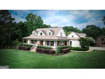 Charming two-story home with a welcoming porch, lush landscaping, and large lawn at 7093 Vaughn Rd, Canton, GA 30115