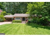 Charming ranch home with a well-manicured lawn, lush landscaping, and a convenient carport at 2917 Rockingham Nw Dr, Atlanta, GA 30327