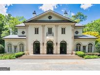 Elegant brick home with arched windows, a balcony, and lush landscaping on a sunny day at 3857 Randall Mill Nw Rd, Atlanta, GA 30327