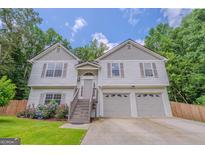 Inviting two-story home featuring a two-car garage and a well-maintained front yard with vibrant flowers at 3781 Deercreek Dr, Powder Springs, GA 30127