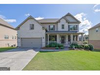 Inviting two-story home featuring a brick facade, covered front porch, lush lawn, and attached two car garage at 4520 Odum Lake Trl, Cumming, GA 30040