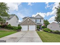 Charming two-story home with a two-car garage, stone accents, manicured lawn and inviting curb appeal at 142 Holly Mill Village Dr, Canton, GA 30114