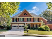 Charming two-story brick home features a manicured front lawn, two-car garage, and classic architectural details at 4729 Woodland Brook Se Ct, Atlanta, GA 30339