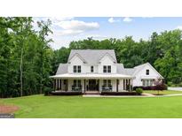Charming white farmhouse with a welcoming front porch and professionally landscaped yard at 2101 Thomas Rd, Canton, GA 30115