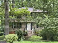Two-story home exterior with mature trees, dark shutters, and a white front door at 372 Nalley Dr, Stone Mountain, GA 30087