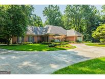 Sprawling single story brick home with mature trees, luscious lawn, and a horseshoe driveway at 3030 Spalding Dr, Sandy Springs, GA 30350