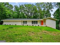 Charming one-story home with a brick facade, green lawn, and colorful front door at 3332 St John Dr, East Point, GA 30344