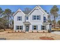 Charming two-story home with light-blue siding, dark shutters, brick foundation, and well-manicured landscaping at 3614 Squires Park Ln, Loganville, GA 30052