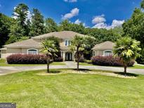 Stunning home featuring a circular driveway, lush landscaping, and mature palm trees at 345 Peaceful Way, Fayetteville, GA 30214
