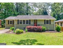 Charming single-story home with a well-manicured lawn, blooming shrubs, and a welcoming red front door at 2985 Westbury Dr, Decatur, GA 30033