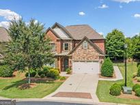 Charming two-story home featuring a brick and stone facade, well-manicured lawn, and a two-car garage at 3015 Arbor Song Ct, Cumming, GA 30041