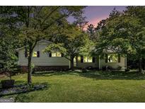 Charming ranch home featuring a well-manicured lawn and lush trees at dusk at 2067 Skyhawk Ln, Acworth, GA 30102