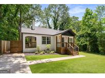 Charming renovated bungalow with white painted brick, dark trim, a new roof, a lovely front porch, and lush landscaping at 345 Adelle Se St, Atlanta, GA 30315