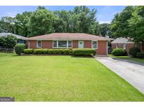 Charming brick home with a well-maintained lawn and mature landscaping at 135 5Th Ave, Jonesboro, GA 30236