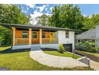 Charming home with a wood-accented porch, yellow door, painted brick, and a well-manicured front lawn at 1400 North Avenue Nw, Atlanta, GA 30318