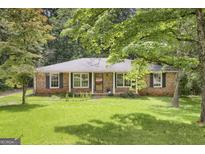 Charming brick home with mature trees and a lush, well-maintained front lawn at 3180 S Elizabeth Dr, Douglasville, GA 30135