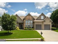 Charming home featuring stone accents, a well-manicured lawn, and a two-car garage at 1511 Rocky Knoll Ln, Dacula, GA 30019
