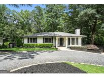 Charming single-story home featuring a gravel driveway, manicured lawn, and classic white brick facade at 2676 Cottonwood Dr, Marietta, GA 30066