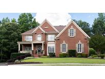 Charming brick home featuring manicured lawn, complementing shrubbery, and a welcoming entrance at 200 Long Needle Ct, Sugar Hill, GA 30518