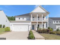 Charming two-story home featuring a welcoming double porch and attached two-car garage at 129 Academy Ln, Canton, GA 30114