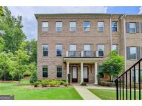 Brick townhome featuring a well-manicured lawn, covered entrance and second story balcony at 711 Topsail Ln, Alpharetta, GA 30005