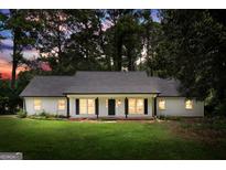 Charming single-story home with a well-manicured lawn, black shutters and columns and mature trees at 2487 Highland Se Dr, Conyers, GA 30013