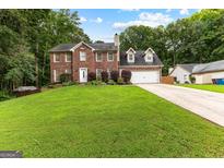 Charming two-story brick home featuring a well-manicured lawn and attached two-car garage at 435 Hampton Grn, Peachtree City, GA 30269