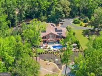 Stunning aerial view of a home nestled among lush trees, featuring a sparkling pool, outdoor seating, and solar panels at 1572 Azalea Dr, Lawrenceville, GA 30043