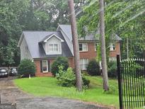 Charming two-story home featuring brick facade, gabled roof, landscaped front yard, and iron gate for added curb appeal at 423 Orchards Walk, Stone Mountain, GA 30087