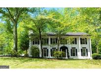 Classic two-story house with columns and surrounded by mature trees and lush greenery, creating a serene and inviting atmosphere at 909 Ne Otter Way Ne Way, Marietta, GA 30068
