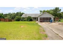 Lush front lawn, driveway, and mature trees in a ranch-style home at 1587 Cronic Town Rd, Auburn, GA 30011