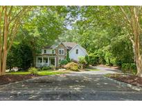 Charming home with a stone and siding exterior, covered porch, and a circular driveway surrounded by mature trees at 1788 River Bluff Vw, Duluth, GA 30097