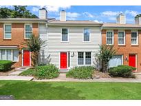 Charming townhouse with a bright red door, complimented by lush greenery in a well-manicured front yard at 191 High Creek Dr, Roswell, GA 30076