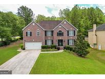 Charming two-story brick home with a well-manicured lawn, a two-car garage, and a beautiful landscaped front yard at 10038 Hemlock Way, Jonesboro, GA 30238