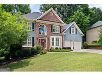 Charming two-story home with a combination of brick and siding, complemented by a well-manicured lawn and mature trees at 5418 Amity Dr, Powder Springs, GA 30127