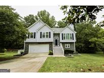 Charming two-story home with stone accents, white siding, black shutters, and well-maintained landscaping at 7030 Wessex Way, Cumming, GA 30028