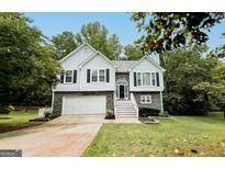 Charming two-story home featuring a stone facade, white siding, and a well-manicured lawn at 7030 Wessex Way, Cumming, GA 30028
