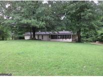 Quaint single-story home with a lush green lawn and mature trees creating a serene, private setting at 125 Highland Cir, Stockbridge, GA 30281
