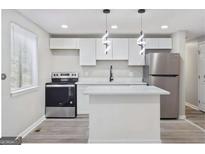 Modern kitchen featuring stainless steel appliances, white cabinets, and a kitchen island at 2106 Singer Way, Lithonia, GA 30058