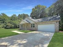Charming single-story brick home featuring a two-car garage, manicured lawn, and inviting curb appeal at 243 Roxbury Dr, Riverdale, GA 30274