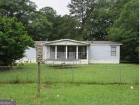 Charming single-story home with a covered front porch, well-maintained lawn, and mature trees at 322 Loblolly Ridge, Locust Grove, GA 30248