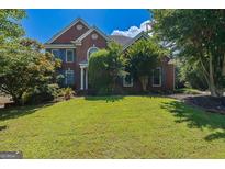 Traditional brick home with manicured lawn and mature trees and blue shutters at 901 Chadwick Park Dr, Lawrenceville, GA 30045