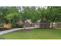 Beautifully landscaped front yard with lush grass and mature trees framing the brick home and driveway at 11940 Wexford Club Dr, Roswell, GA 30075