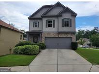 Charming two-story home featuring stone accents, gray siding, a two-car garage, and manicured landscaping at 2424 Saint Andrews Rdg, College Park, GA 30337