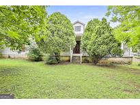 Charming home featuring a quaint front porch framed by lush greenery and mature trees at 936 Bo Bo Banks Rd, Grantville, GA 30220