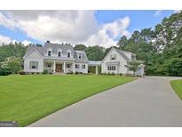 Stunning two-story farmhouse with a lush lawn, a long driveway, and attached garage at 5187 Lower Fayetteville Rd, Sharpsburg, GA 30277